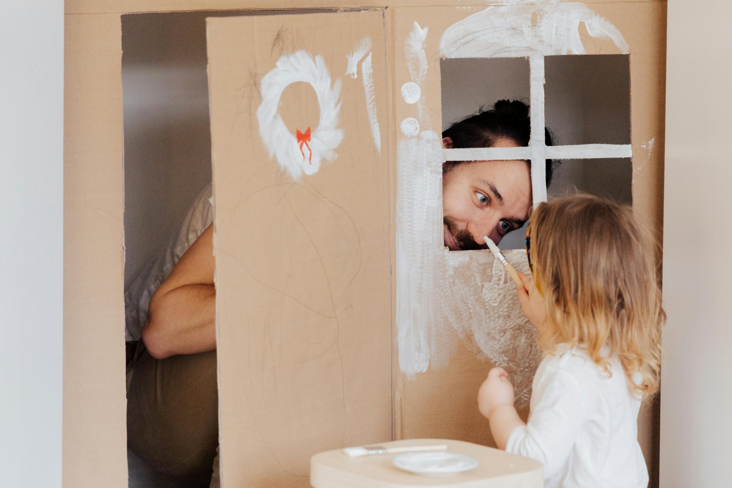 padre haciendo una casa de carton con su hija